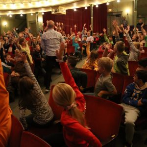 kids enthusiastically raising their hands during an event at the ramsdelll theatre